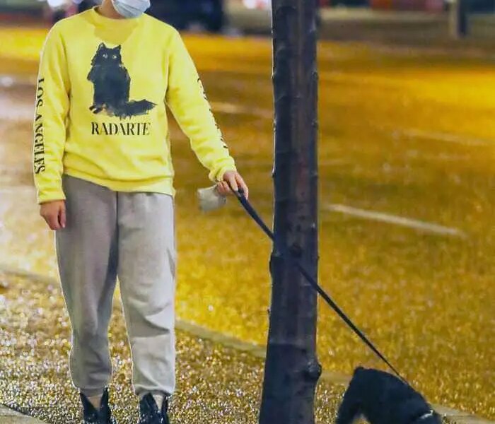 Lili Reinhart in the Yellow Sweatshirt as She Takes her Dog Out for an Evening Stroll